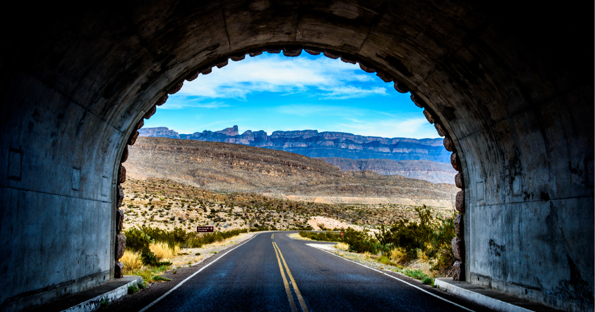 A road leading out of a tunnel toward mountains, illustrating company vision quotes and the path to business success.
